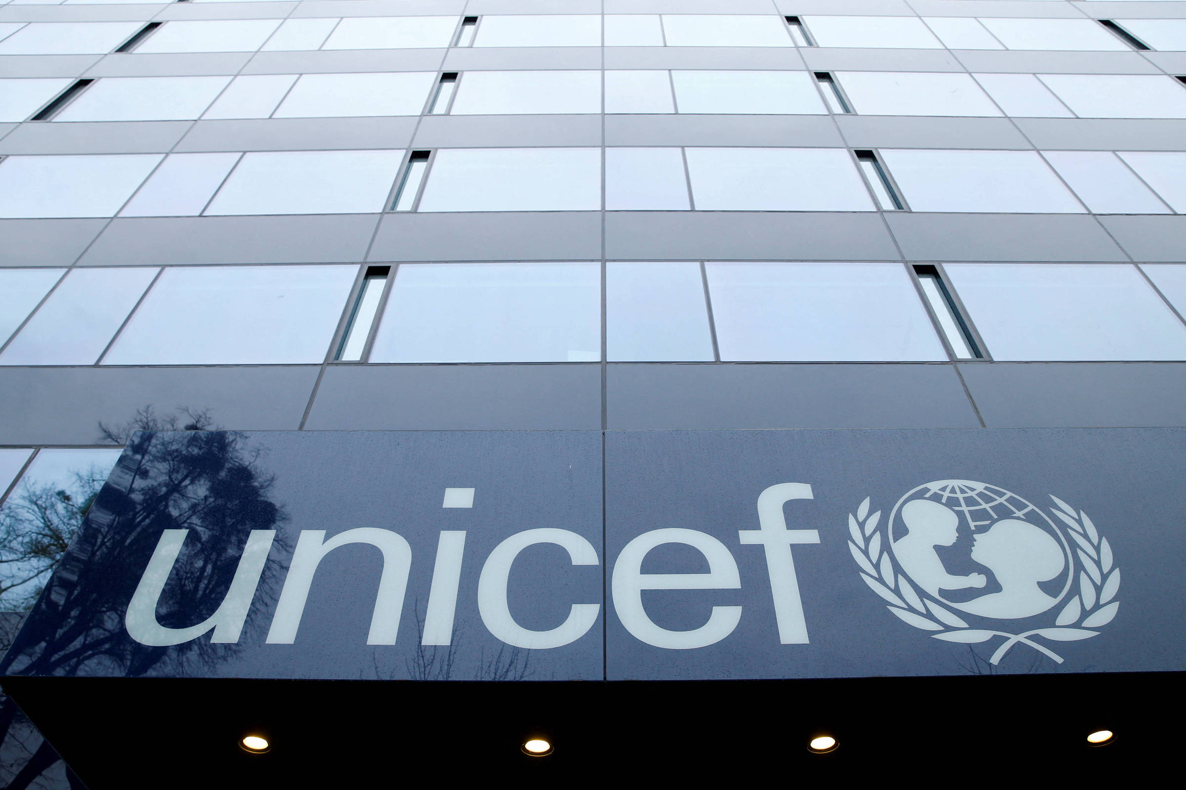 A imagem mostra a fachada de um edifício com o logotipo da UNICEF em destaque. O logotipo é composto pela palavra