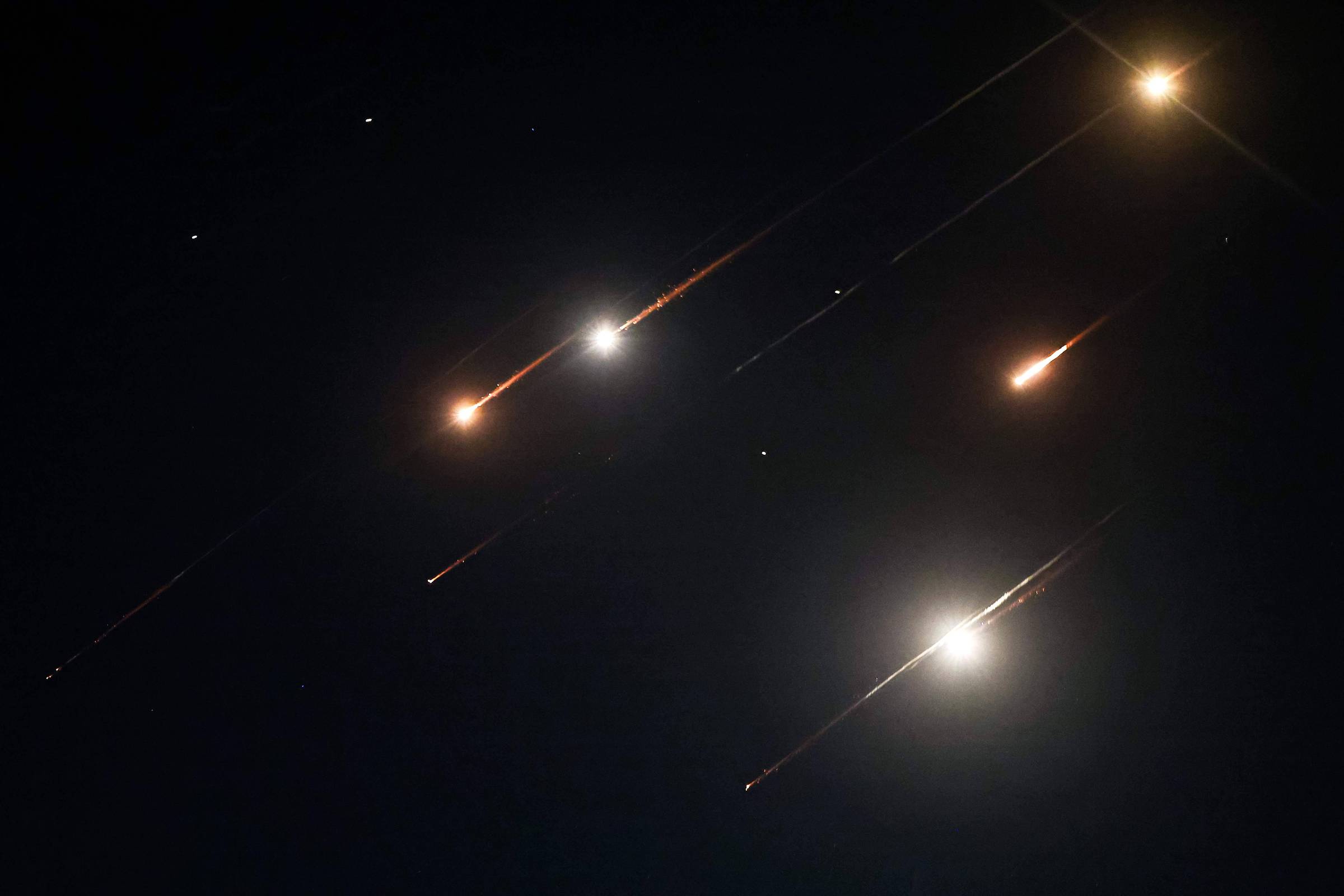 A imagem mostra um céu noturno com várias estrelas visíveis, algumas delas com rastros luminosos que indicam movimento. As estrelas estão dispostas em diferentes posições, criando um efeito visual dinâmico. O fundo é predominantemente escuro, destacando as luzes das estrelas.