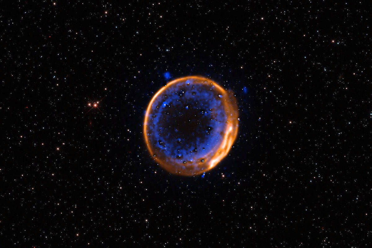 A imagem mostra uma nebulosa esférica no espaço profundo, cercada por um fundo repleto de estrelas. A nebulosa apresenta uma borda luminosa em tons de laranja e azul, com uma estrutura interna que parece ter uma textura irregular. O fundo é predominantemente negro, pontilhado por estrelas brancas e algumas mais brilhantes, criando um contraste com a nebulosa.
