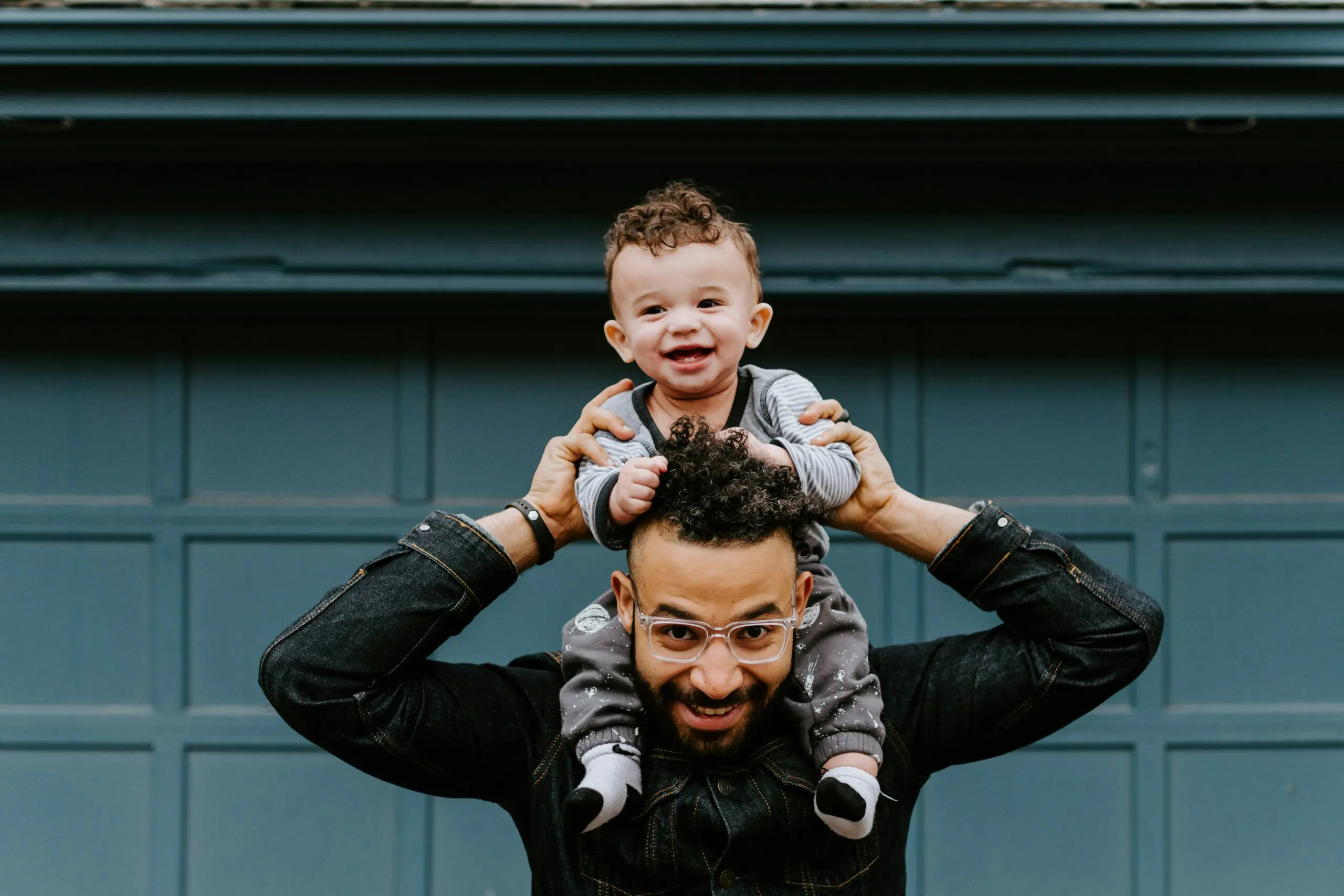 Pai e filho comemorando o dia dos pais. O homem está brincando com seu filho e ambos estão sorrindo.