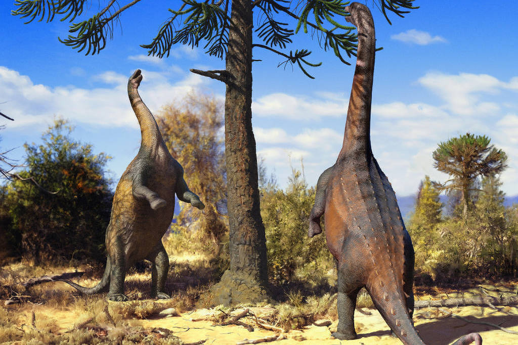 A imagem mostra dois dinossauros herbívoros, possivelmente sauropodes, em um ambiente pré-histórico. Eles estão se aproximando de uma árvore alta, com folhas verdes. O cenário é árido, com vegetação baixa e algumas árvores ao fundo. O céu é azul, com algumas nuvens brancas.