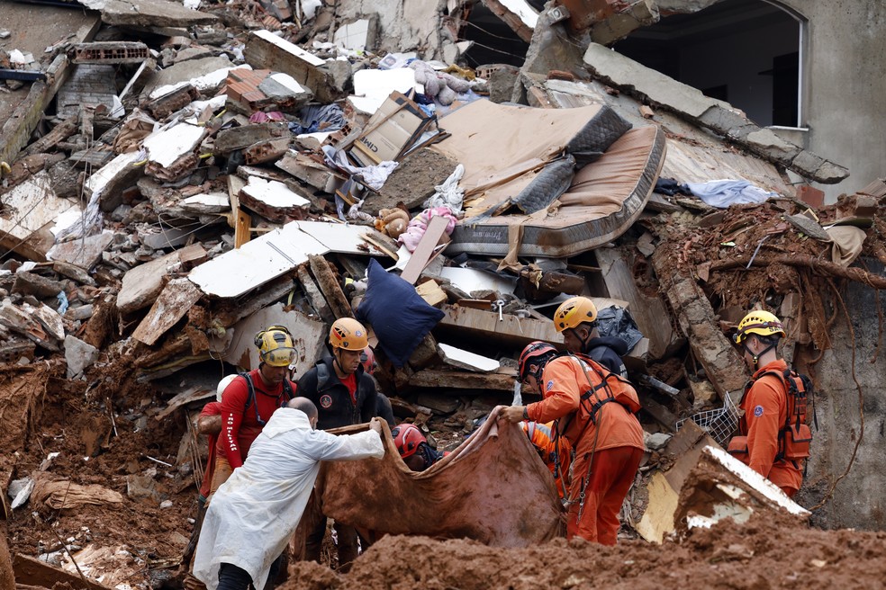 Soldados do Corpo de Bombeiros e voluntários fazem busca e resgate de pessoas em escombros de casas soterradas por lama após fortes chuvas, em Juiz de Fora (MG) — Foto: Tânia Rêgo/Agência Brasil