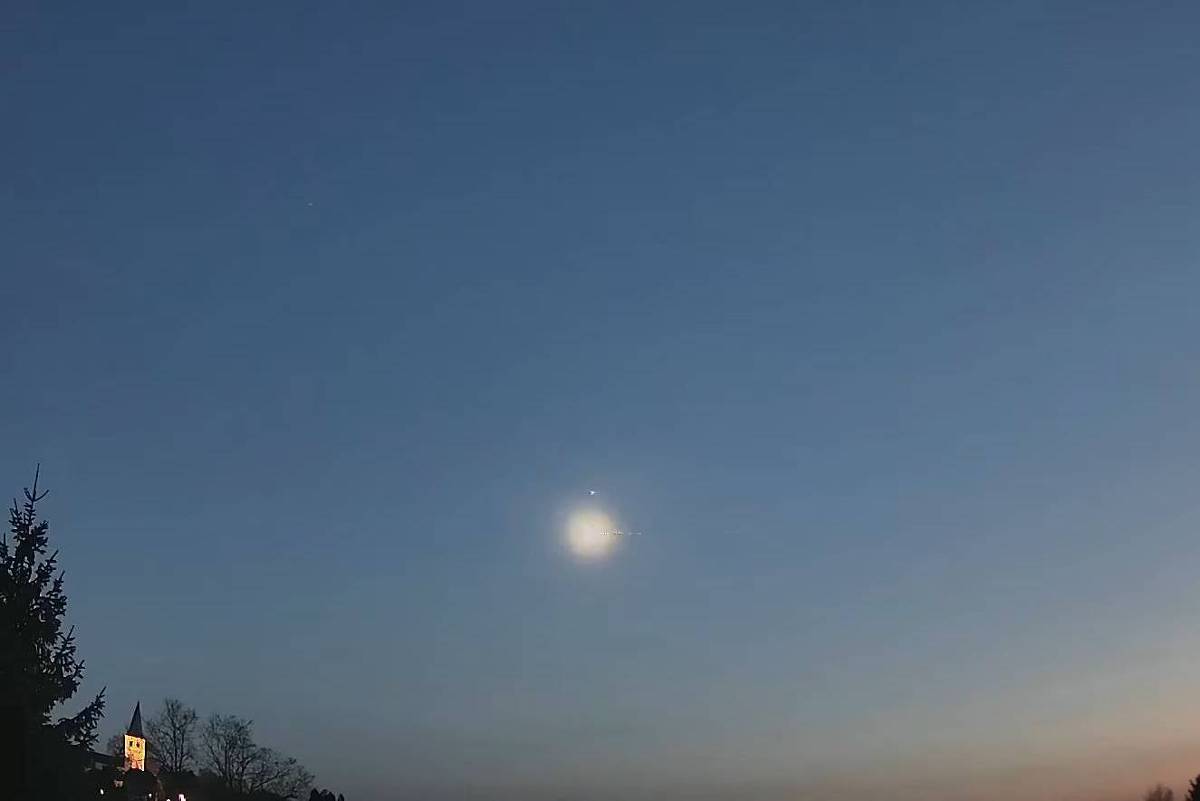 Ponto brilhante no céu azul, em paisagem com algumas árvores