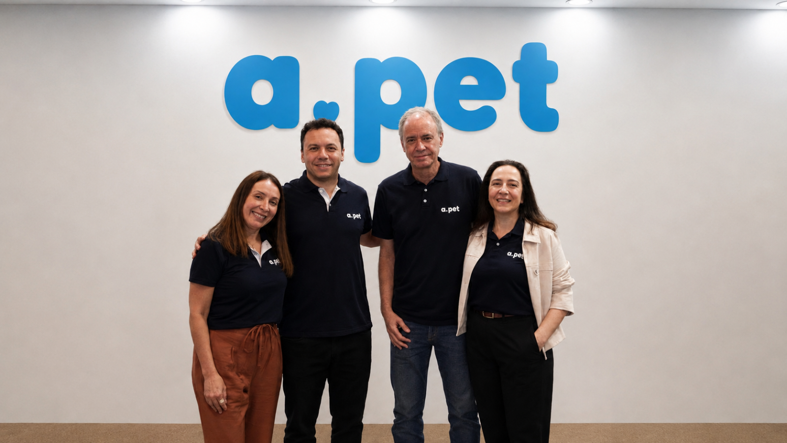 Equipe da APet reunida na sede da empresa, diante da identidade visual da marca.
