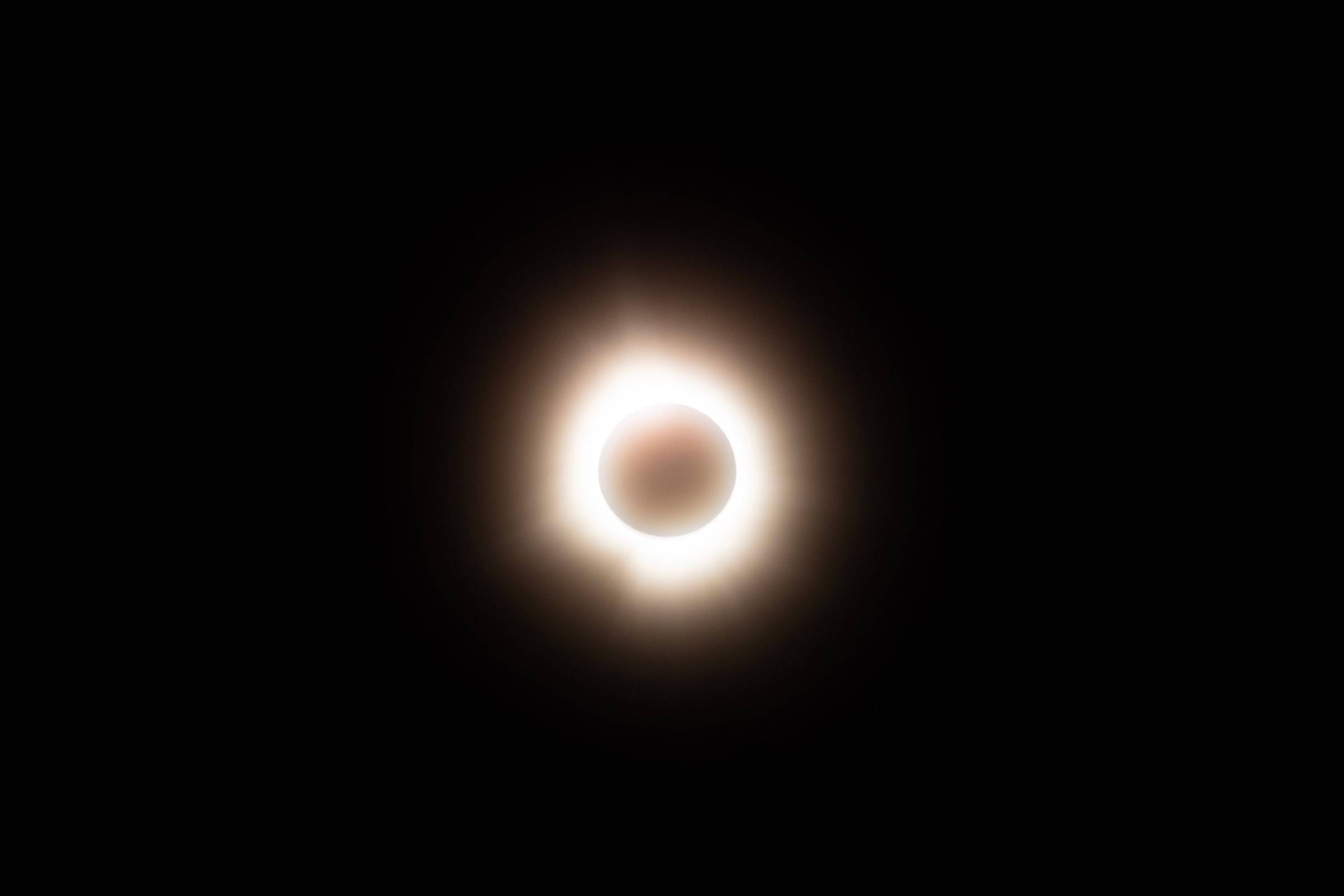 Eclipse solar anular com o disco da lua cobrindo o centro do sol, formando um anel brilhante ao redor em fundo preto.