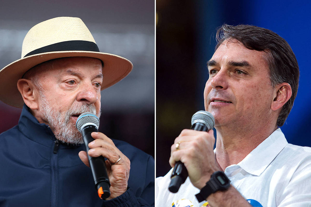 À esquerda, homem de barba grisalha usa chapéu claro e jaqueta escura enquanto fala ao microfone. À direita, homem de cabelo castanho curto veste camisa branca e segura microfone em evento com fundo azul.